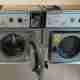 A photo of a several washing machines in a laundromat. The one immediately in front of the camera has its door open.