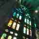 Looking up at some stained glass windows in la Sagrada Família. The near ceiling is faceted and coloured green and blue from the window light.