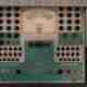 A photo of the front of a vintage ‘tube tester’. The camera is looking directly down on a control panel. There’s dials and inputs all over, with a large swinging gauge in the center.