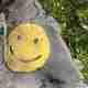 A yellow circle painted on a rock, with a smiling face in the middle.