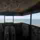 Photo taken from within a small room with exposed opening on all side - a panoramic view of the channel and eastuary.