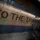 A sign painted on some old cream tiles reads ‘to the trains’