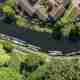 A drone photo of a canal. The camera is facing straight down. There are canalboats on one side.