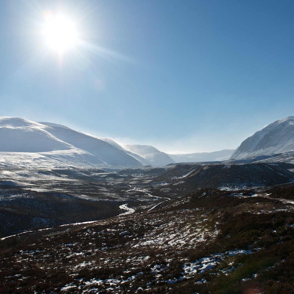 A wide panorama of the Gleann Eanaich valley. There’s snow on the upper parts of the mountains and in the valley it’s mostly brown.