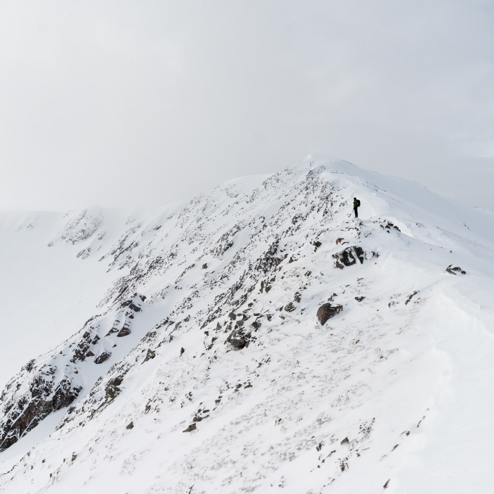 Ed in the distance looking down over a snow covered ridge.