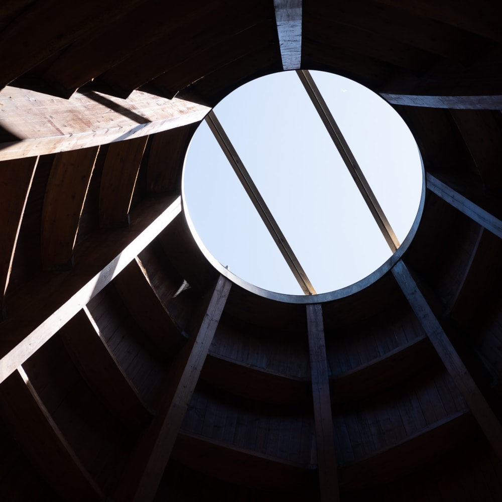 Looking up to a circular opening in a wooden roof.