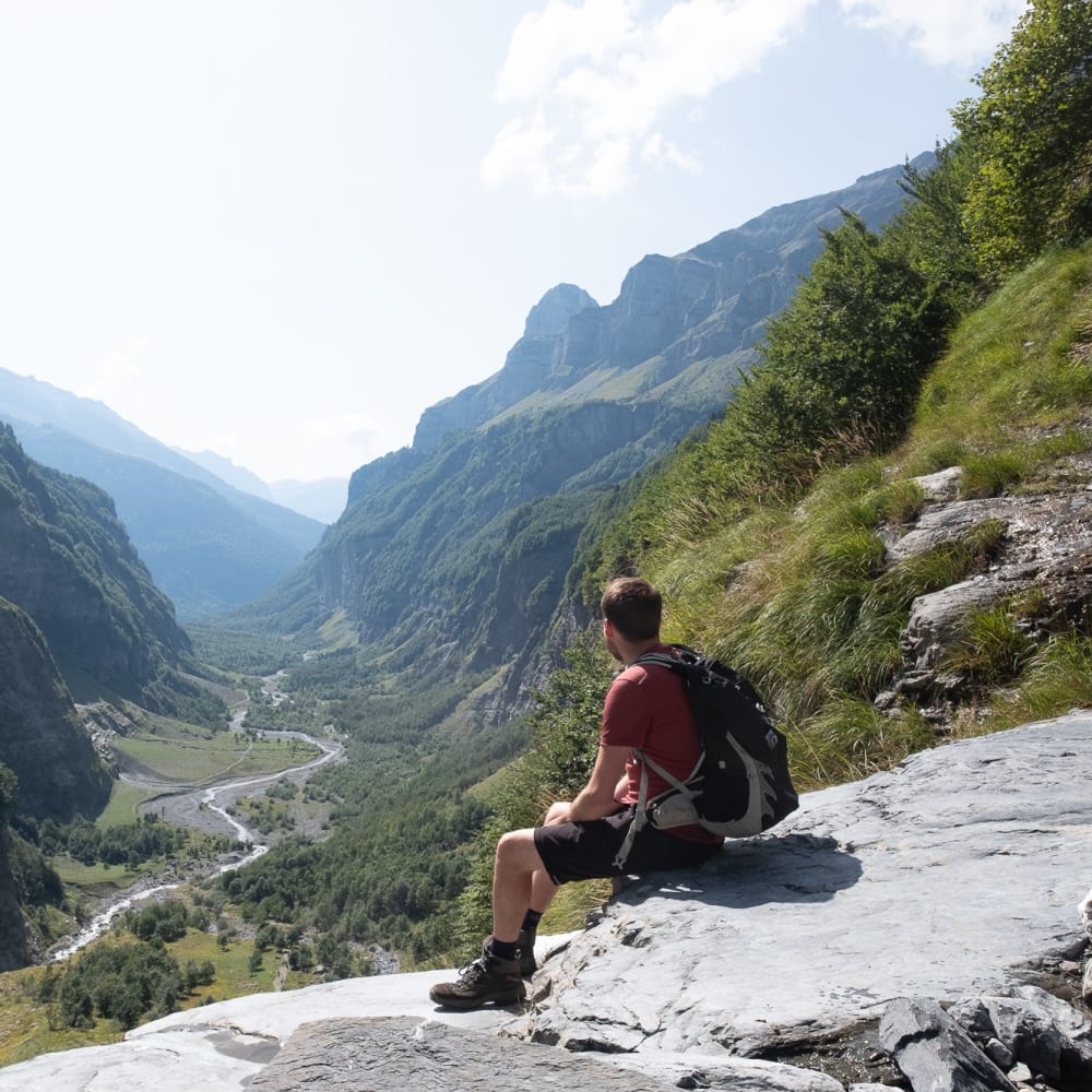 Ed sat on a large rock, overlooking a large and deep valley.