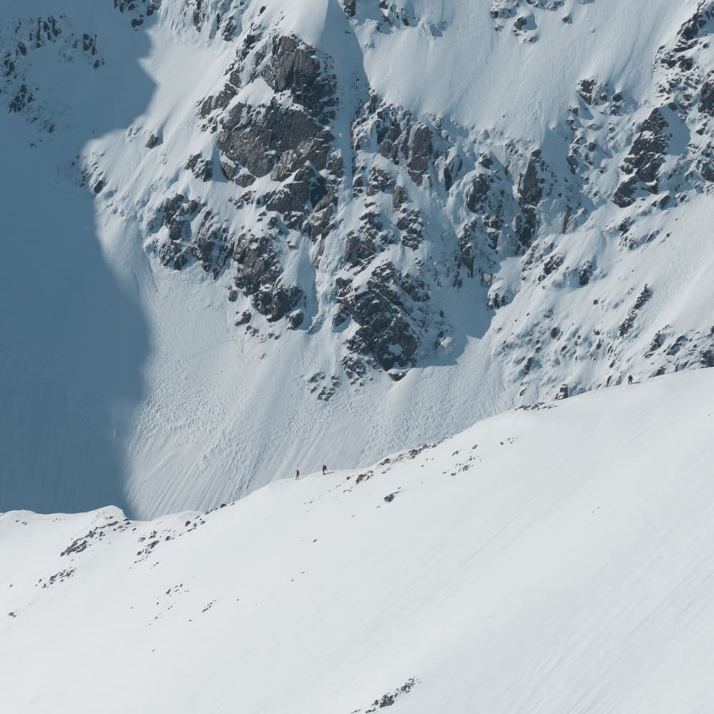 A high zoom photo looking towards a section of the CMD arete on a sunny day. Tiny figures can be seen descending it.