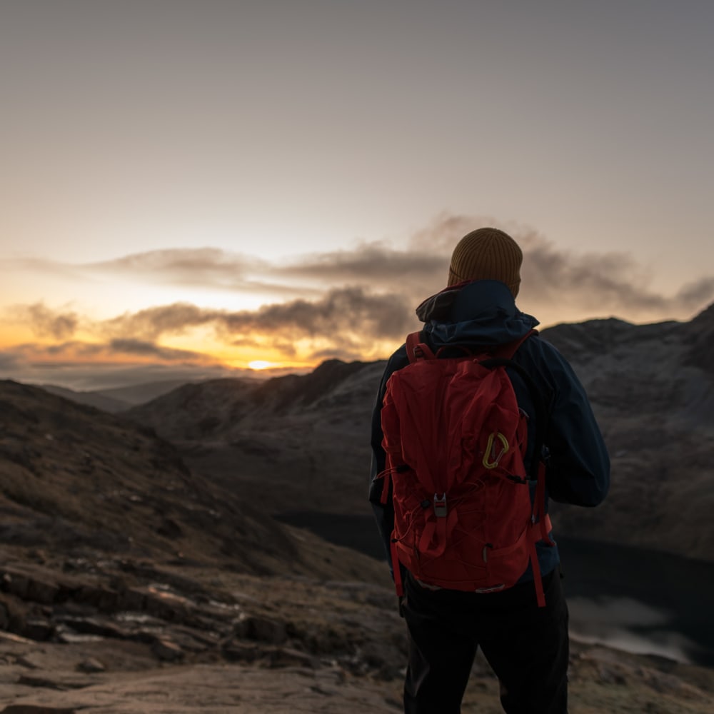 Ed facing away from the camera just before sunrise. He’s got a bright backpack on.