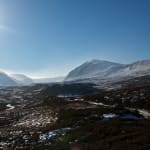 A wide panorama of the Gleann Eanaich valley. There’s snow on the upper parts of the mountains and in the valley it’s mostly brown.