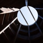 Looking up to a circular opening in a wooden roof.