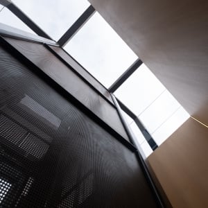 Looking up at a wooden stairwell with large skylight.