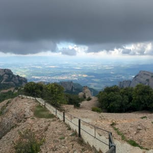 A panorama taken a the top of Sant Jeroni in Montserrat. The sky is gloomy but clear skies can be seen in the distance.