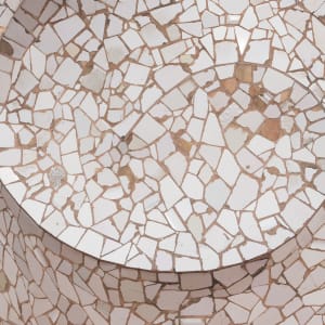 A close photo of a mosaic at Casa Milà. The tiles are roughly broken and all white - they’re arranged in a spiral pattern.