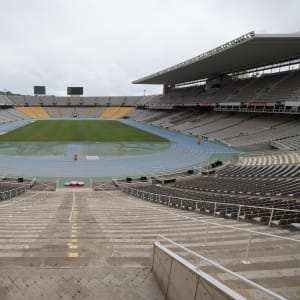 A photo of the olympic stadium in Barcelona. The photo is taken from one end, looking in to the main arena. There are seats all around and the playing field in the centre.
