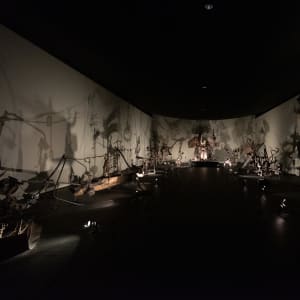 A dark room filled with many eery metallic sculptures by Jean Tinguely.