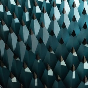 A photo of some radio-wave insulating foam. The foam is formed in to tall pointy pyramids with pale blue bases and black tips. The pyramids are arranged in a rigid grid - as if the entire floor were spikey.