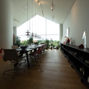 Looking towards a window inside the Vitra showroom. The room has a profile like a house with a pointed roof. Inside the room is a long table and bench.