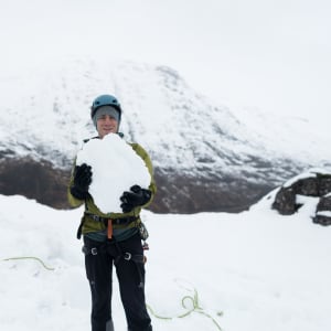 Chris holds a large boulder of snow as he faces the camera.