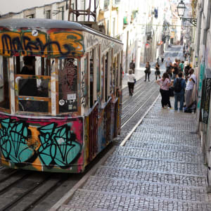 A funicular car descending a steep street in bright sunlight.
