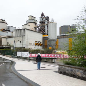 Lynn stands in front of the Rezola cement factory. There’s a winding cycle path in front of her.