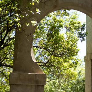Looking through a circular arch between two pillars to some trees beyond.