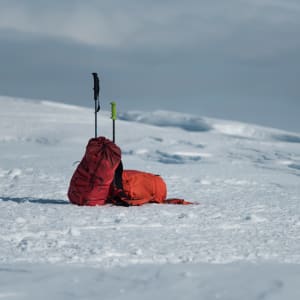 Two climbing bags lean against each other - deserted on a snowy plateau.