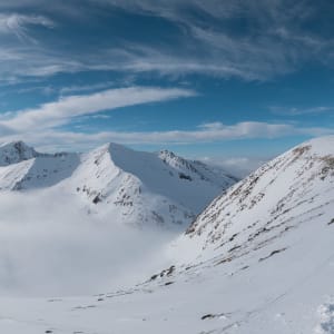 A panorama taken from Aonach Mòr looking towards Ben Nevis. The sky is sunny and deep blue, and there’s a cloud inversion, so the ground isn’t visible.