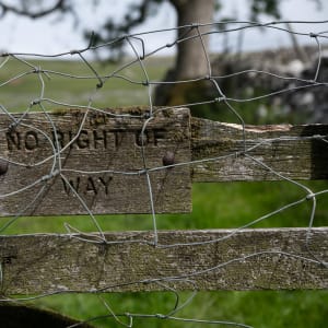 An aged wooden sign on a fence says ‘No right of way’ - it’s also covered in chicken wire.