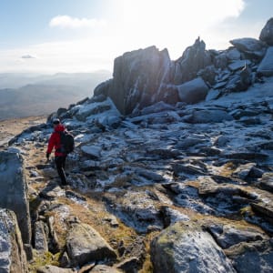 Chris descends a gently sloping hillside covered in large frost-covered boulders.