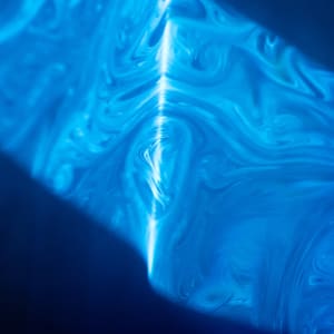 Smoke swirls are lit up by laser beams in blue.