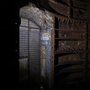 Dimly lit doorway with sign to stairs and metal bulkheads to the side.