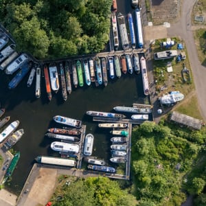Drone photo looking straight down at a canal boat mooring. There’s dozens of boats all lined up side by side.