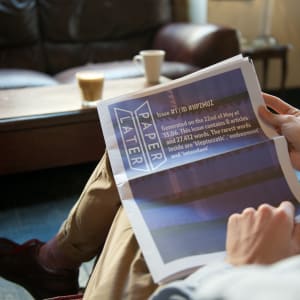 A man reading a PaperLater newspaper in a coffee shop.
