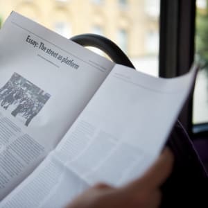 Photo of a PaperLater newspaper being read on a bus.