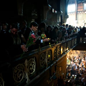 A man drops yellow flower petals over a balcony.