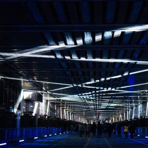 A photo looking straight down the covered Beech Street. The photo is dark, with white criss cross lights on the ceiling, receding into the distance.