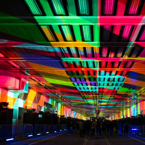 A photo looking straight down the covered Beech Street. The entire ceiling is covered with a patchwork of bright projected colours.