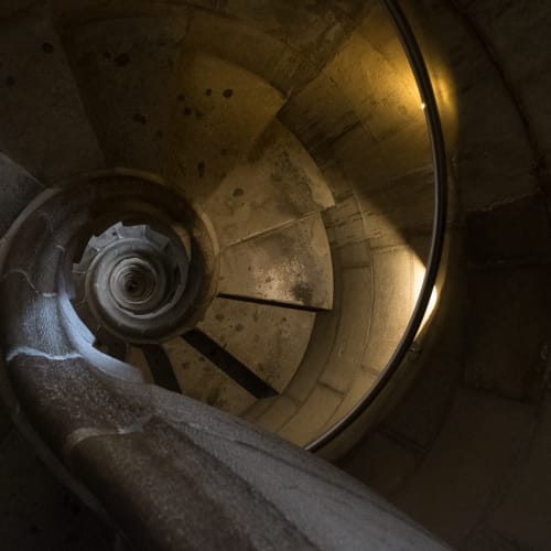 Looking directly down a tight stone spiral staircase