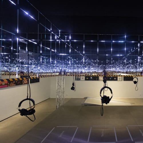 A view inside an art installation at the Vitra Design Museum. There’s mirrors ahead and on the sides creating an infinite loop. The room is dark, but small squares of light repeat.