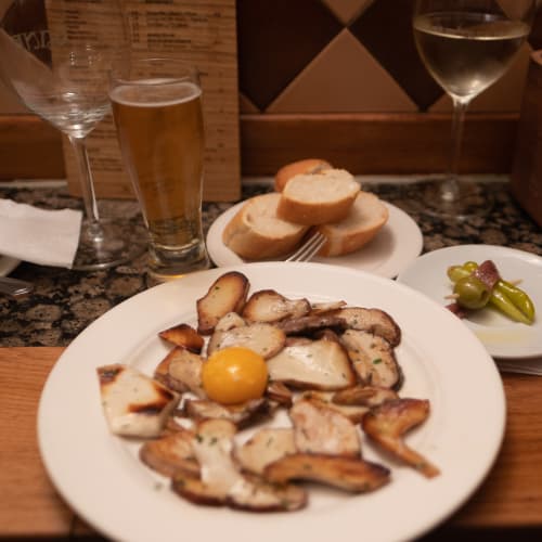 A plate of fried mushrooms with an unbroken egg yoke in the centre.
