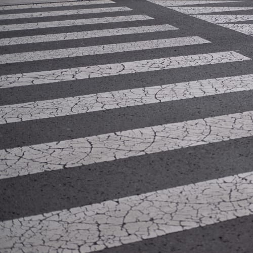 Cracked white markings on tarmac. They’re in a regular grid pattern with arrows at one end.