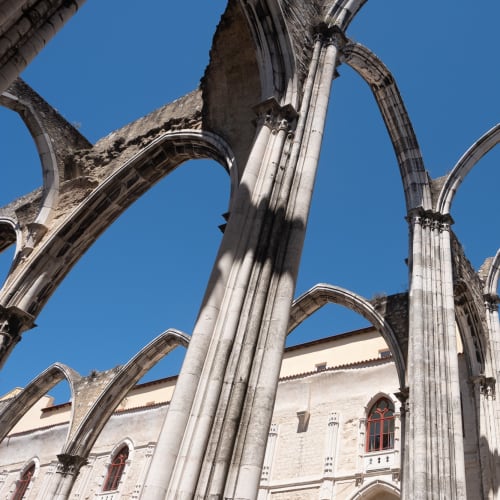 Looking up at the ruins of the Carmo Convent. All that remains are the arches of the building, with blue sky where the ceiling would be.