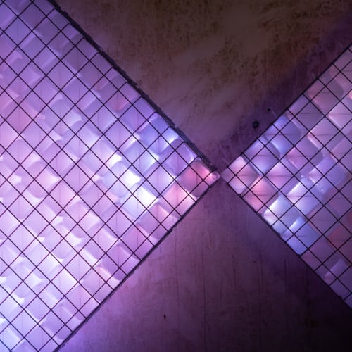 A close photo of a light sculpture. It is made up of small light coloured cubes which are glowing shades of blue and pink.