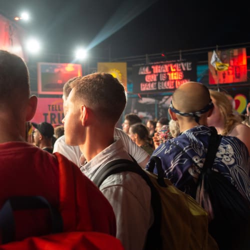 Oj and Rogan wait in a crowd for a band to start.