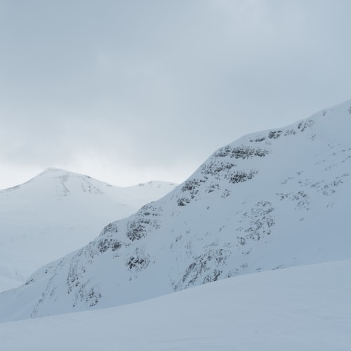 A low contrast view of several snowy ridges.
