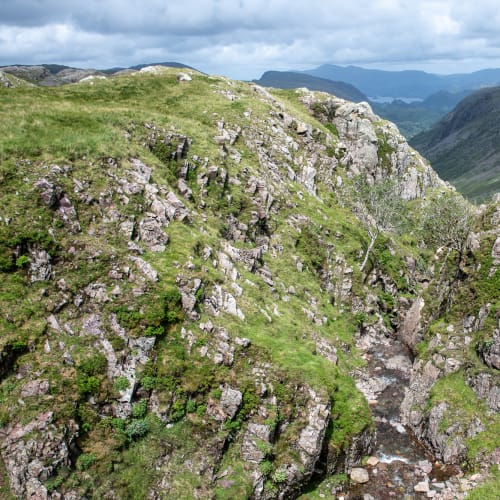 A small crevasse in the hillside, with a stream running through the middle.