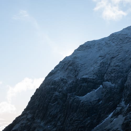 The summit of snowdon seen from just below. The summit is in shadow with a light dusting of snow.