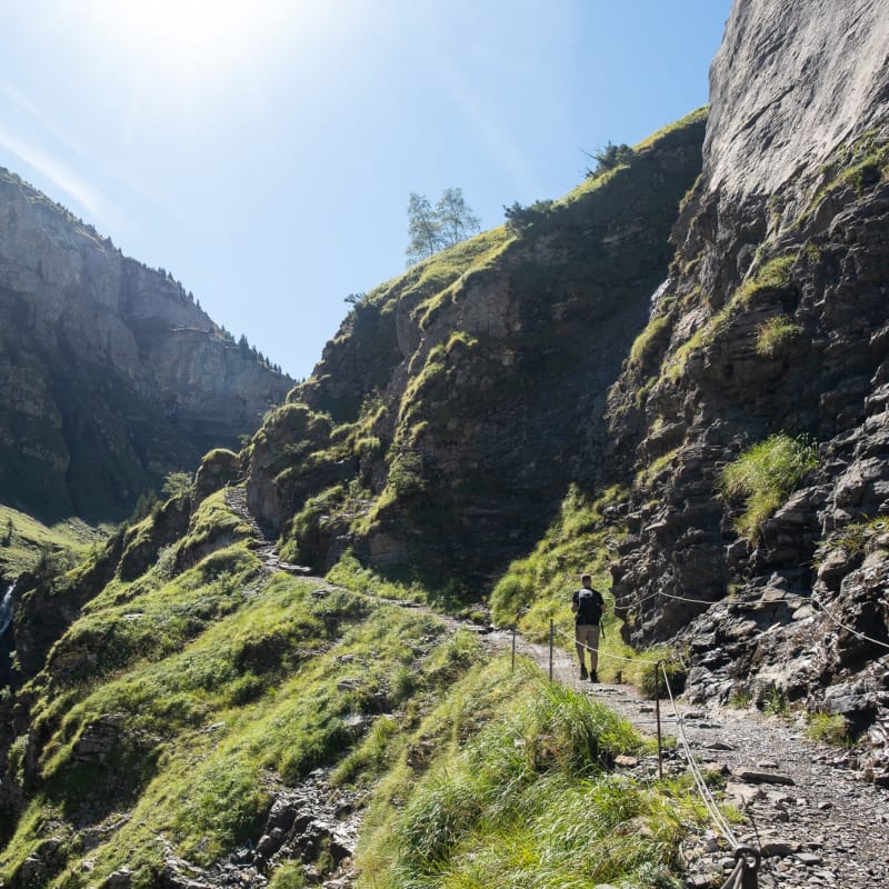 Looking up a valley. A path ascends the valley on the right, with Oj walking half way up it.