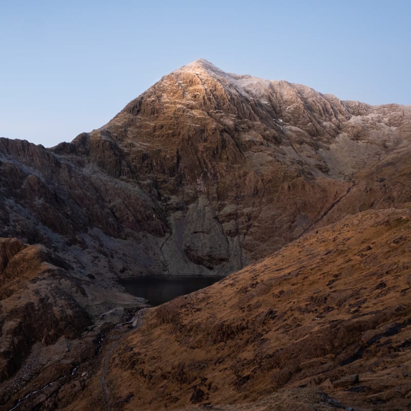 The jagged face of snowdon before sunrise. The mountain has a light dusting of snow on the top.